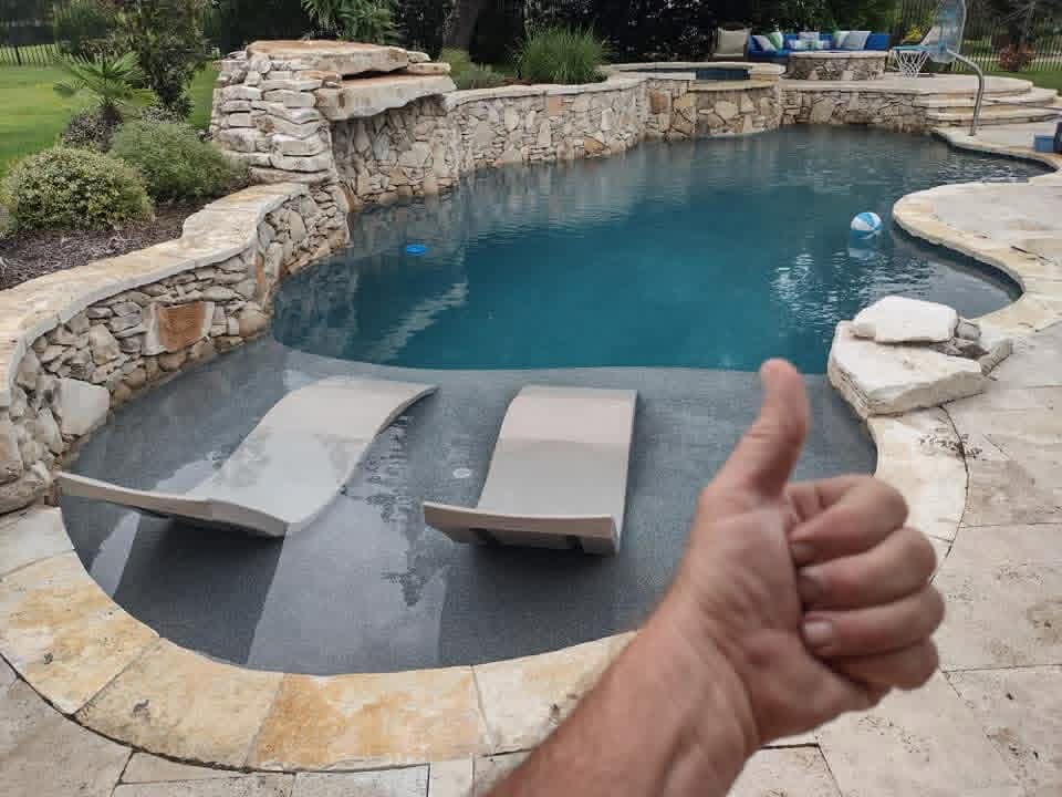 Stone-walled pool with in-water tanning loungers — premium pool maintenance by The Pool Police, Austin TX
