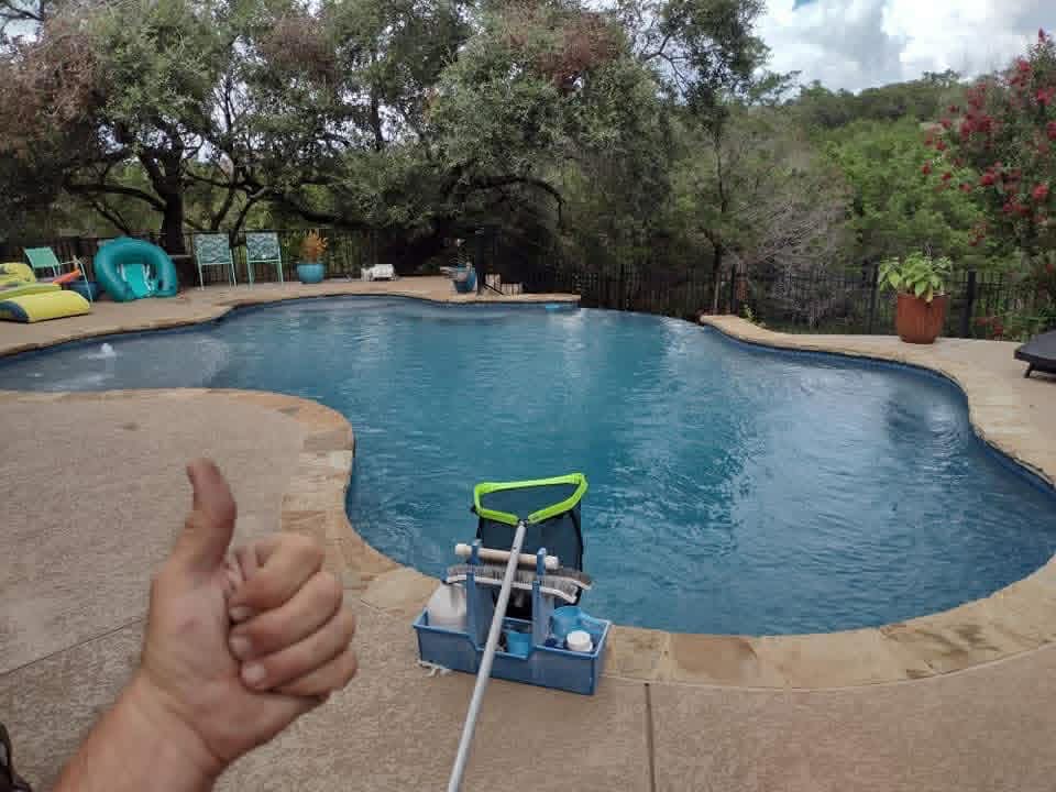 Crystal-clear residential pool with cleaning gear and skimmer net — weekly visit complete, by The Pool Police